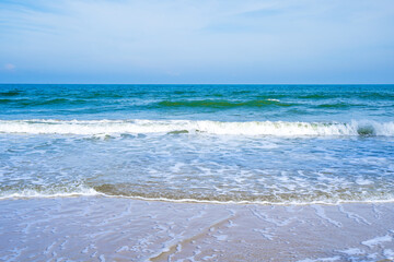 Light blue sea waves on a clean sandy beach..