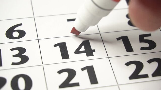 Writing RED HEART on 14th February on calendar with a red marker. The concept of Valentine's day