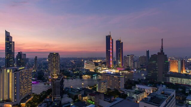 Sunset over illuminated landmark building in downtown and cruise ship on Chao Phraya riverside in Bangkok