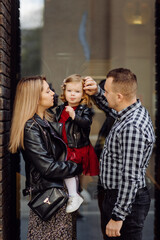 Obraz premium Parents and daughhter walking around the city. Spend time together. They are happy