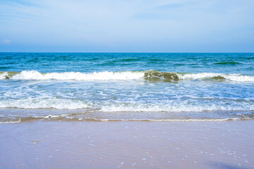 Light blue sea waves on a clean sandy beach..