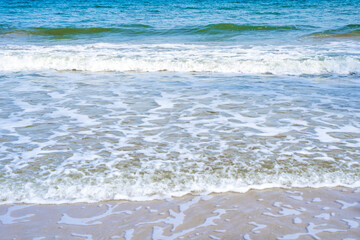 Light blue sea waves on a clean sandy beach..