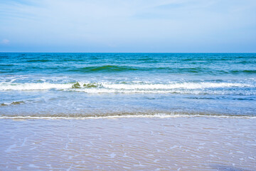 Light blue sea waves on a clean sandy beach..