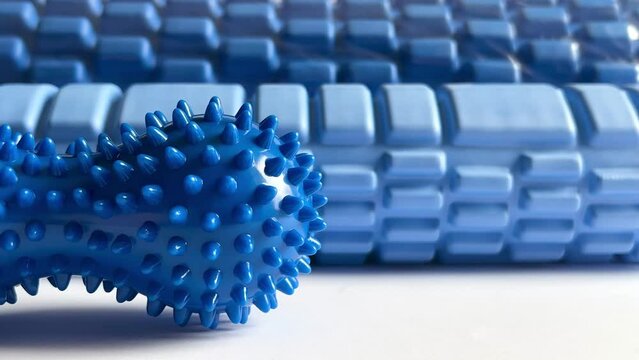 A blue foam massage roller. Blue double or peanut spikey ball massager for yoga pilates or stretching and fascia pain. Myofascial release. Gym fitness equipment.