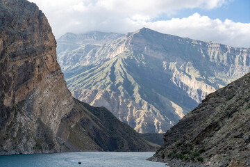 Motor boat on scenic turquoise river among rocks and mountains. Confluence of Avar koysu and Andi koysu into Sulak river.