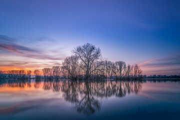 Sunset on the shore of a natural natural landscape lake in northern Europe. Reflections, blue sky and yellow sun. Landscape during sunset.