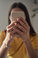 Close up of unrecognizable caucasian teenage girl browsing phone while lying on bed
