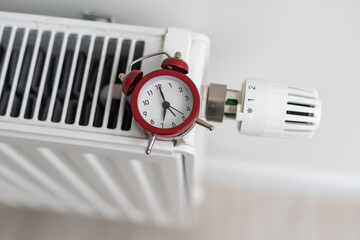 alarm clock on heating radiator against light background. Space for text.