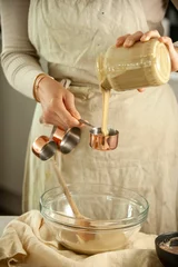 Keuken spatwand met foto Vertical closeup of female hands pouring baking cookie on the glass bowl other ingredients around © Simone Oppes/Wirestock Creators