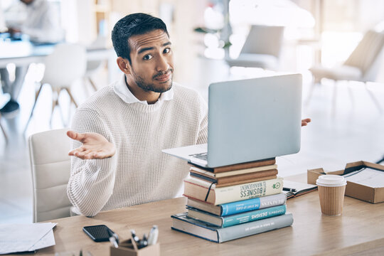 Confused, laptop and multitask with a business man shrugging his shoulders while working in the office. Desk, question and doubt with a male employee multitasking while at work on a stack of books