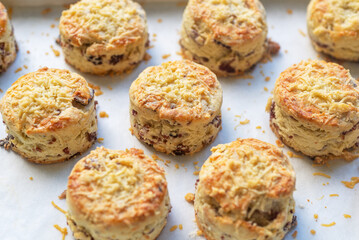 A tray of baked savory bacon scones with a sprinkles of cheddar and parmesan cheese on top