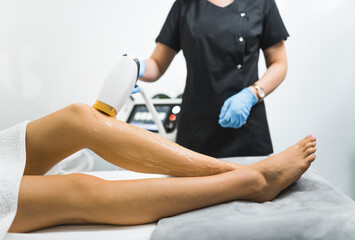 closeup view of a cosmetologist removing hair from a client's legs, laser depilation apparatus, modern technology beauty treatment. High quality photo