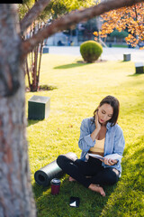 Happy brunette hair sporty woman resting after exercising in park, reading a book. Relax, lifestyle concept. Summer relaxation concept. Healthy lifestyle