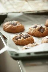 Tuinposter Vertical closeup of freshly baked cookies on the black baking sheet blurred background © Simone Oppes/Wirestock Creators