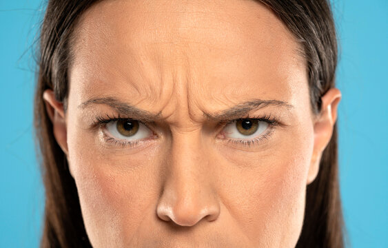 Angry face of a young woman with facial wrinkles closeup
