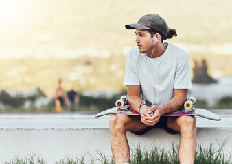 Young man, skateboard and relax outdoor, thinking or chill being casual, trendy and earphones....