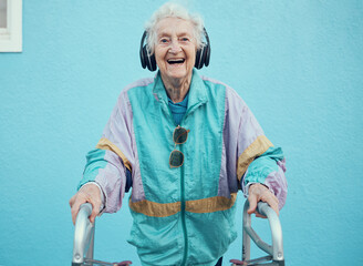 Portrait, hip hop and old woman streaming music, radio or audio with freedom in a cool jacket and headphones. Smile, fashion and happy senior person listening to a song with a blue wall background