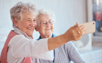 Phone, selfie and elderly friends smile for pictures to share on social media online while relaxing in retirement. Happy, love and senior women smiling while enjoy quality time at home in Berlin