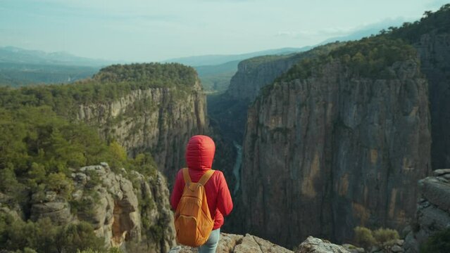 View point of Tazy Canyon. girl standing and admiring stunning scenery in mountains. Tourist woman hiker in red jacket on cliff against backdrop of gorge. Amazing Tazi Canyon, Turkey. Greyhound Canyon