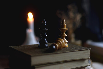 Stack of vintage books, cup of tea or coffee, lit candles, reading glasses and chess pieces on...