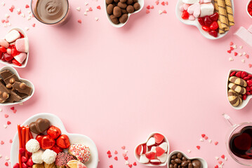 Valentine's Day concept. Top view photo of heart shaped saucers with confectionery candies cookies and glass cups with drinking on isolated pastel pink background with copyspace in the middle