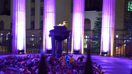Illuminated Shrine of Remembrance with burning eternal flame, flowers on the ground honouring the dead, candlelight vigil night before Anzac day, Brisbane city, Queensland, handheld motion shot. - Powered by Adobe