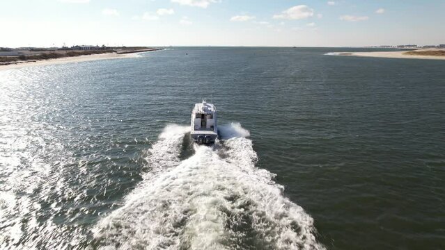 An Aerial View Over The East Rockaway Inlet In Queens, NY On A Beautiful, Sunny Day. The Camera Dolly In, Chasing A Single Small Boat Speeding Out To Sea.