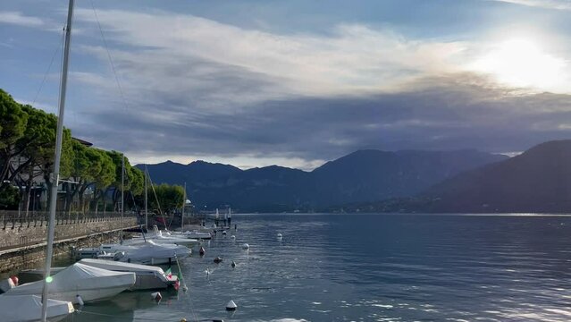Bay front with walkway panoramic lake. Sunise and sun between mountains and clouds. Reflection of the sun's rays in the water
