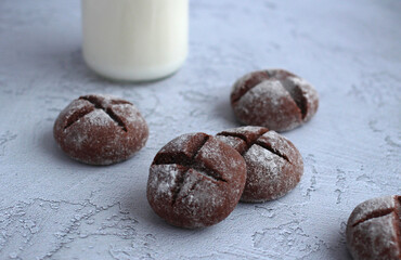 homemade round gingerbread with cinnamon in powdered sugar with milk on a gray background