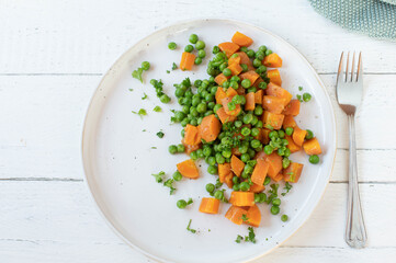 Buttered peas and carrots on a plate isolated on white background