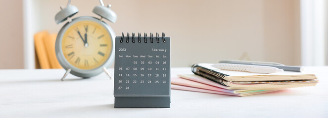 Flip paper calendar with alarm clock and notebooks on table