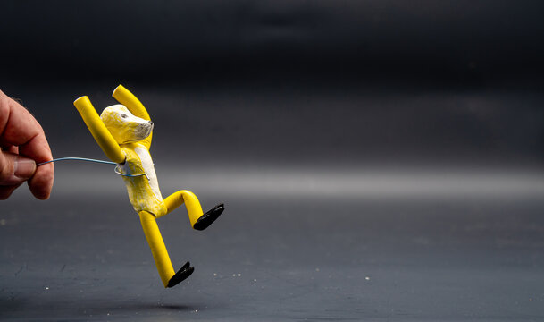 Jump stopmotion process. End of the jump Man's hand holding with an aluminum wire a figure made with yellow modeling paste landing on the ground. The 12 principles of animation.