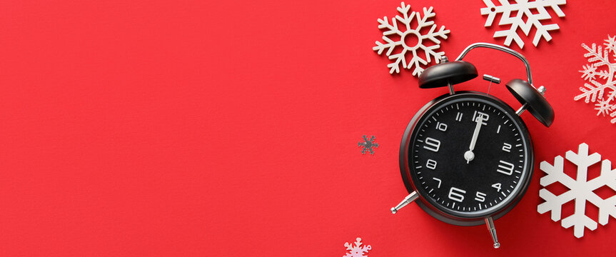 Stylish alarm clock and snowflakes on red background with space for text
