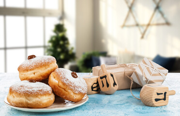 Donuts, gifts and dreidels for Hanukkah on table in room