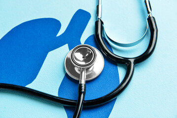 Paper lungs with stethoscope on blue background, closeup