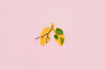 Yellow paper lungs with tree branch and leaves on pink background