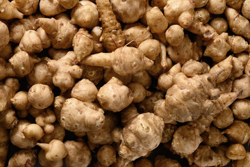 Raw Jerusalem artichoke root, sunchokes as background. View from above.