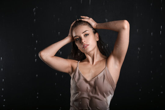 Attractive young woman and dripping water on black background