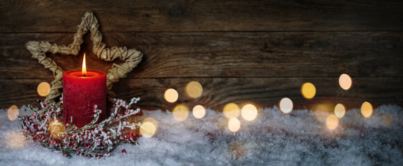 Fototapeta Christmas candle in winter snow landscape with magic lights. Xmas Panorama, Banner. First Advent Sunday. Wood background with copy space. obraz