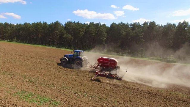 Tractor spreads dry mineral fertilizers on a field of farmland. Aerial shooting