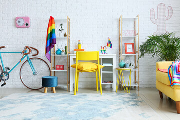 Workplace with bicycle and rainbow flags near white brick wall