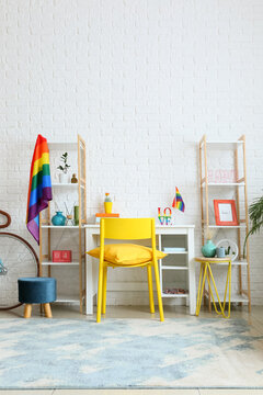 Stylish workplace with rainbow flags near white brick wall © Pixel-Shot