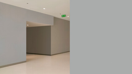 Blank gray wall with emergency exit way on corridor inside of shopping mall in perspective side...