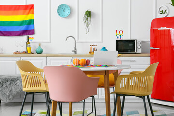 Dining table with modern laptop and rainbow flags in kitchen
