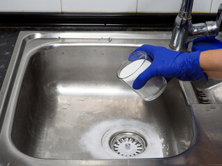Female hand putting baking soda on drain in kitchen sink