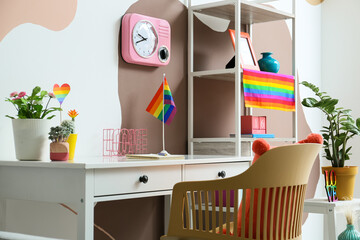 Stylish workplace with rainbow flags near color wall