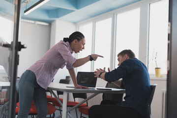 Emotional couple of young colleagues arguing in modern office. African-american business woman shouting at her sad man assistant, copy space, side view