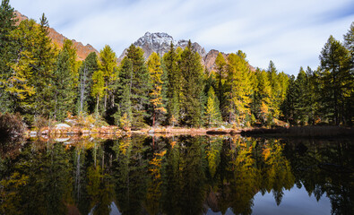 A lake and the mountains in the Swiss alps, during an autumn day near the village of Poschiavo, Switzerland - October 2022.