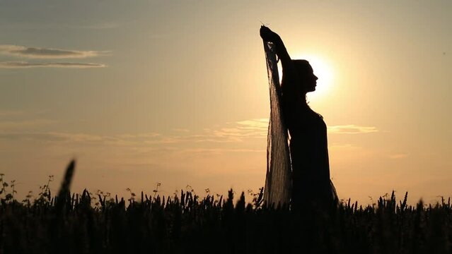 silhouette of a woman dancing with a veil illuminated by the heat of the setting sun