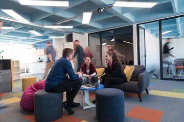 Multiethnic startup business team on meeting in a modern bright open space coworking office. Brainstorming, working on laptop. Group of coworkers walking around in motion blur.